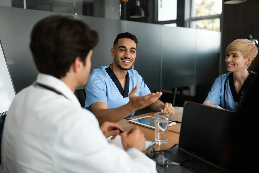 Cheerful young arabic man head physician having team-building with multiracial team of doctors at his office. 